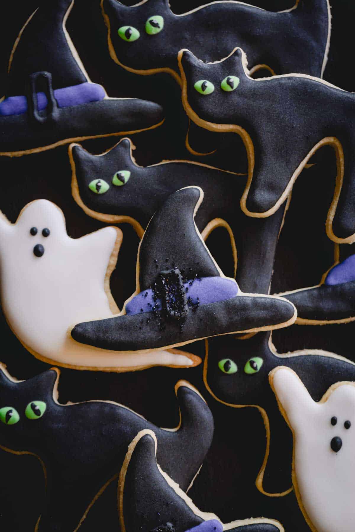 Halloween sugar cookies decorated as ghosts, cats, and witch hats.