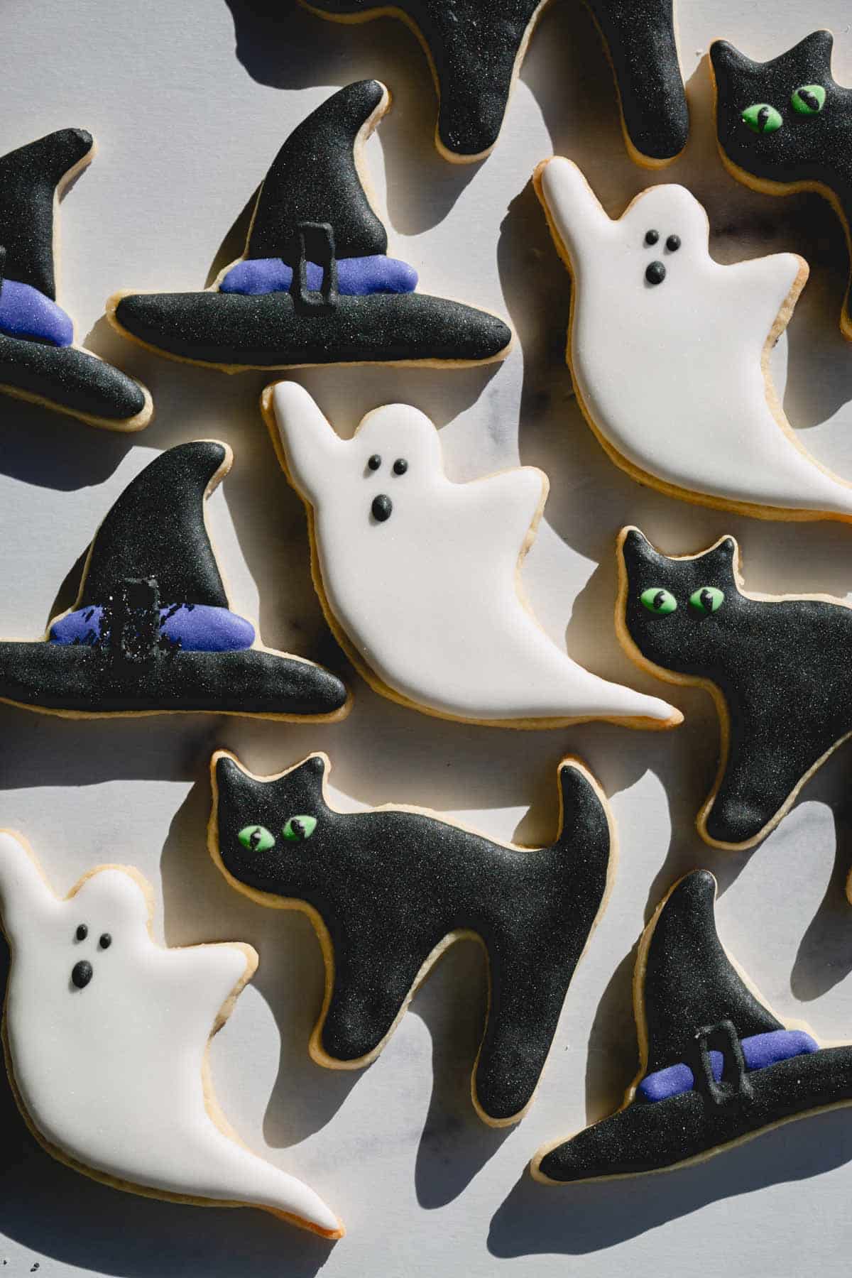 Decorated Halloween sugar cookies as witch hats, ghosts, and black cats.