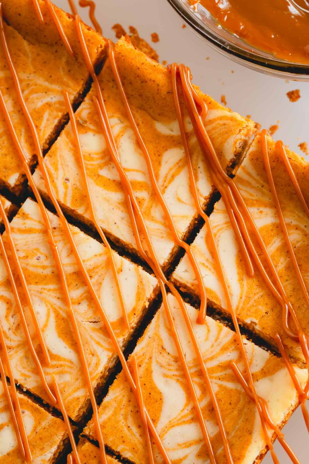 Overhead image of pumpkin cheesecake bars with caramel drizzled on top.