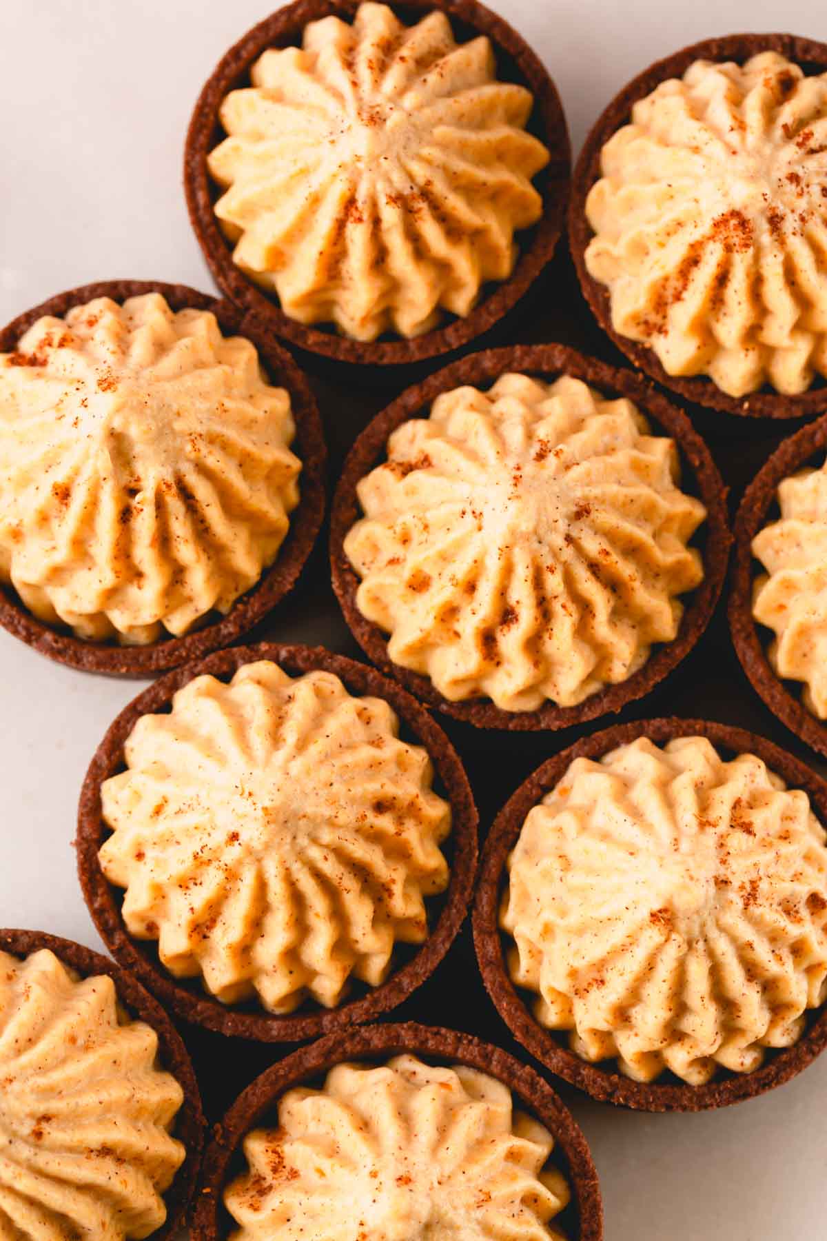 Overhead image of chocolate cups filled with pumpkin mousse and topped with pumpkin spice.