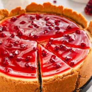 Pomegranate cheesecake with three pieces sliced.