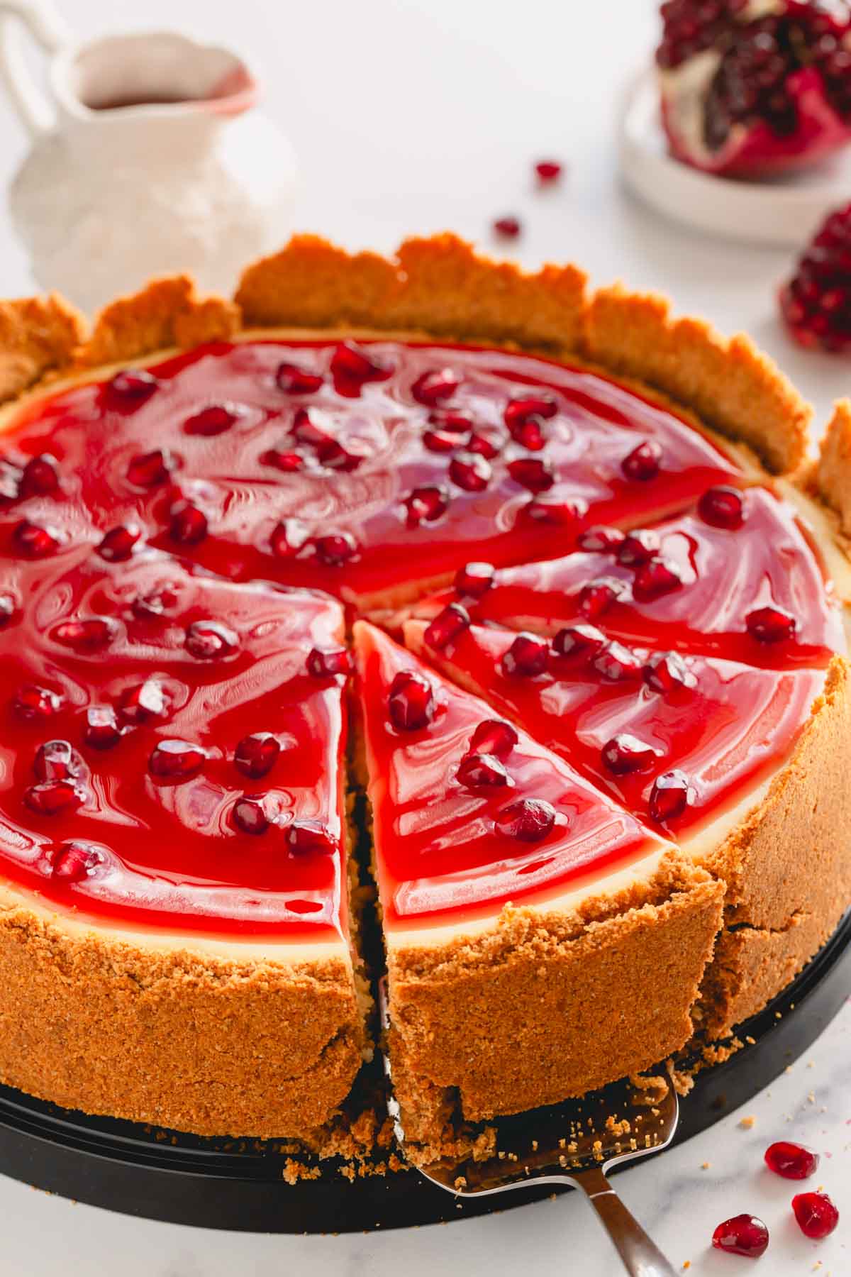 Pomegranate cheesecake with three pieces sliced.