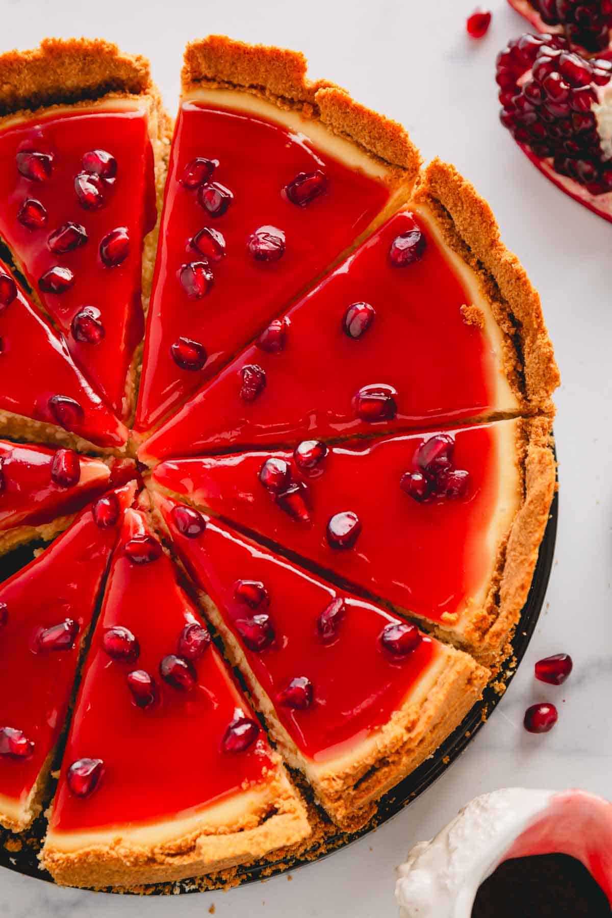 Overhead view of a pomegranate cheesecake topped with pomegranate sauce and seeds.