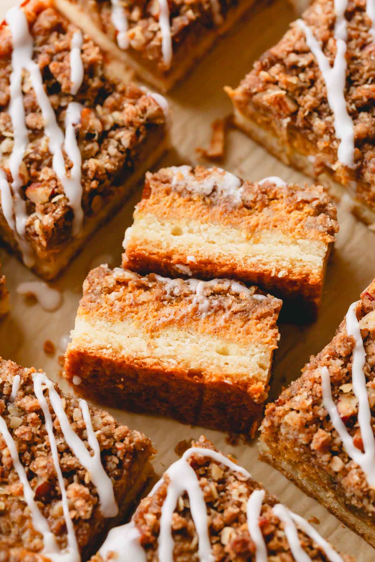 Two pumpkin streusel bars on their side showing the layers of crust and filling surrounded by more bars.
