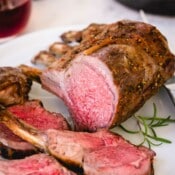 Sliced roasted rack of lamb on a white platter.