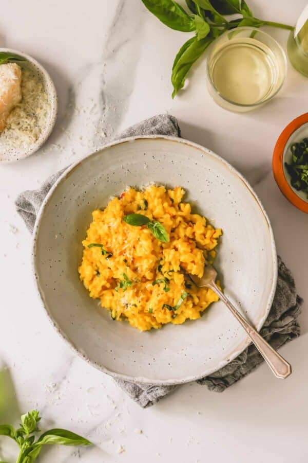 A bowl of saffron risotto with a fork sticking out.
