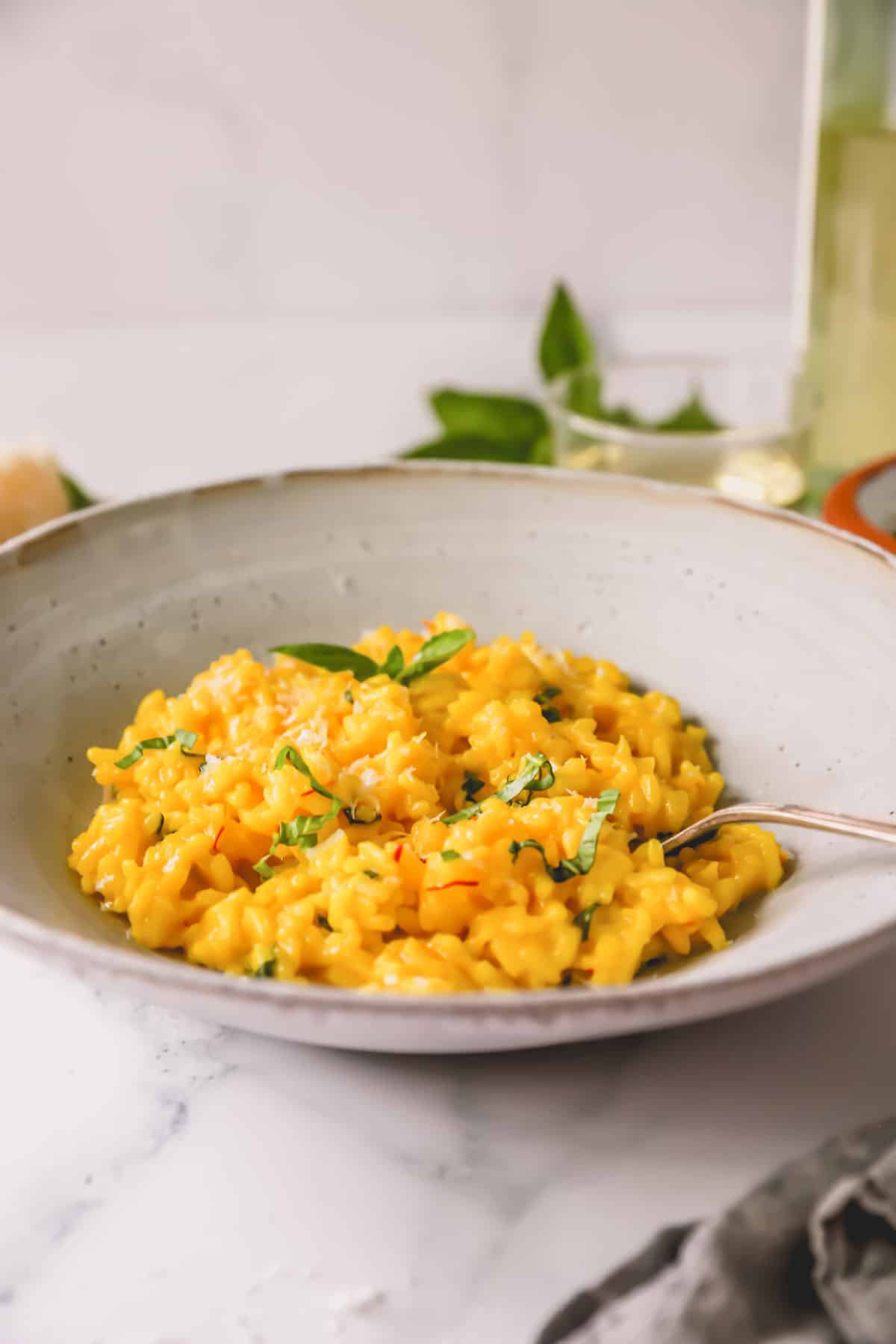 Side view of a bowl of saffron risotto with a spoon sticking out.