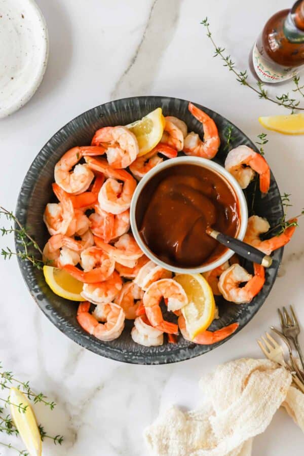 A bowl of cocktail shrimp with cocktail sauce in the center.
