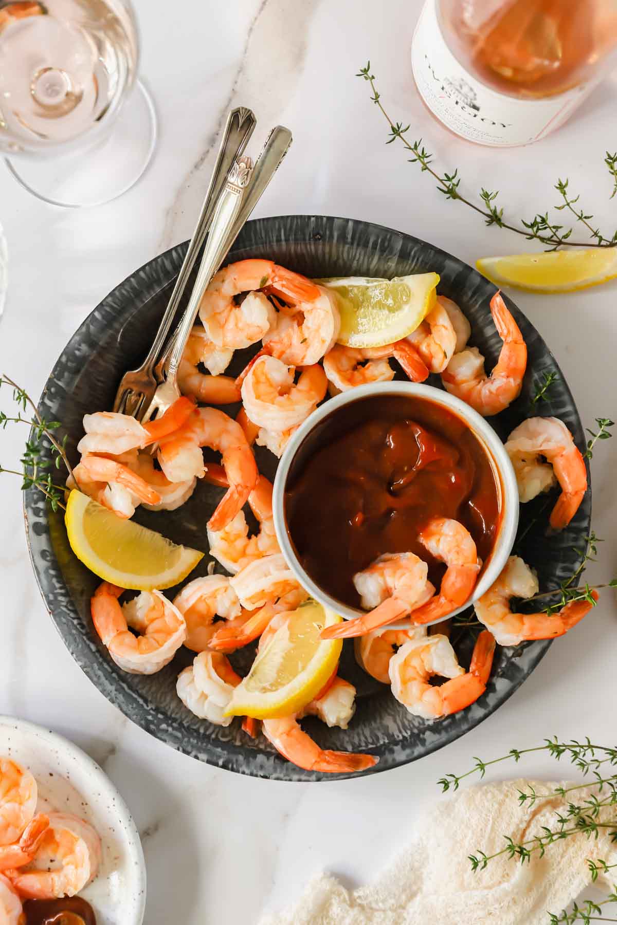 A bowl of shrimp cocktail with cocktail sauce and two shrimp dipped into the sauce.