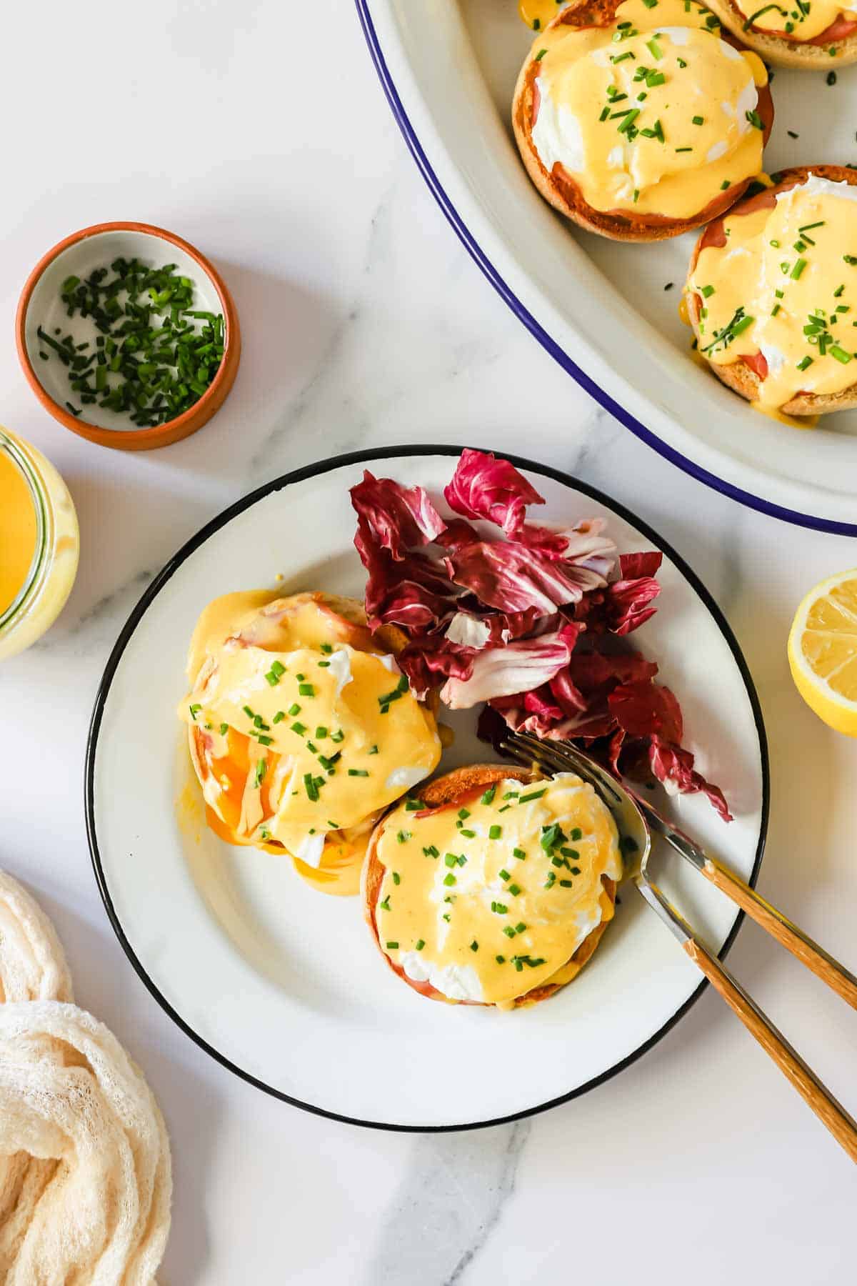 A plate with eggs benedict and red cabbage.
