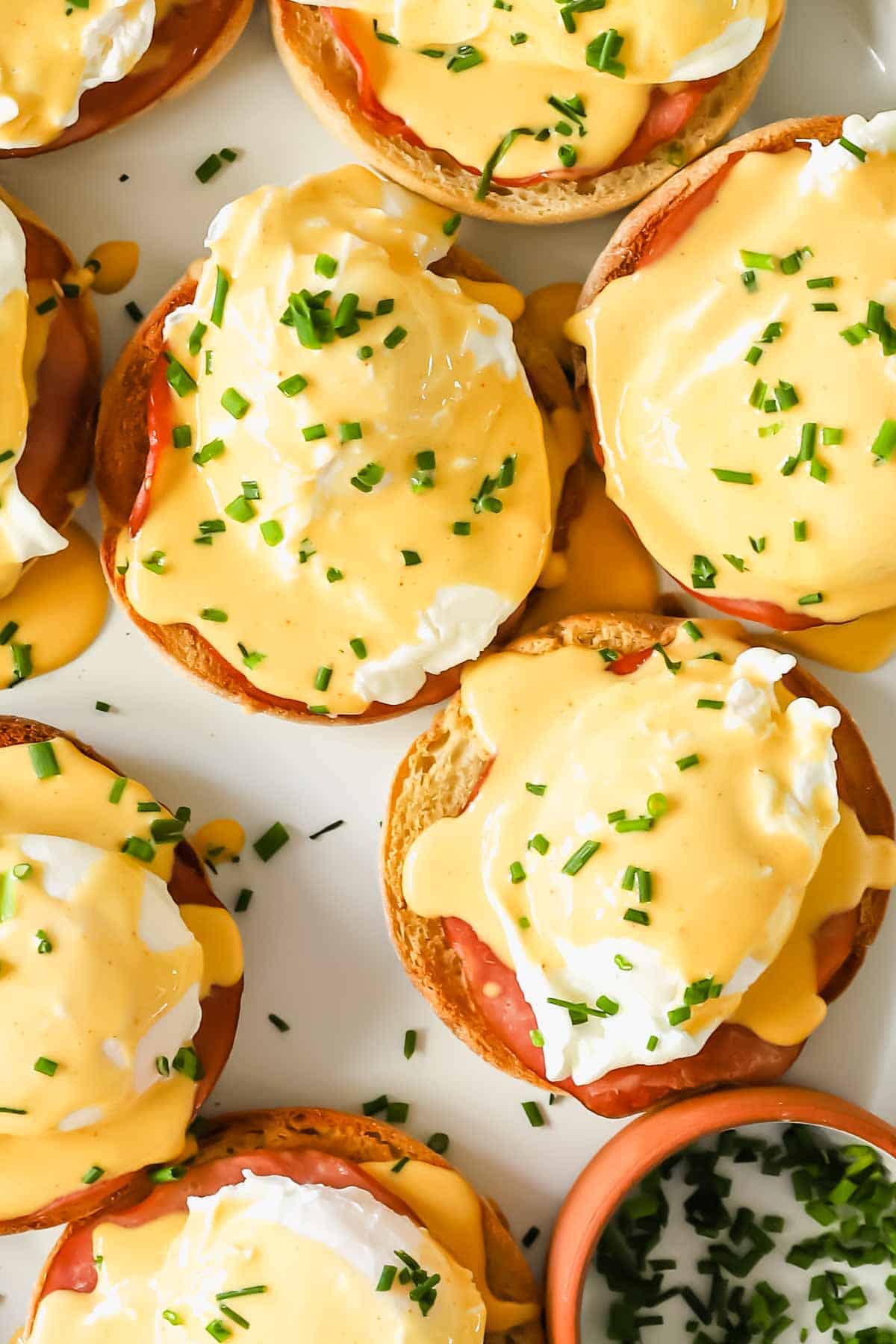 Close view of eggs benedict topped with fresh herbs.