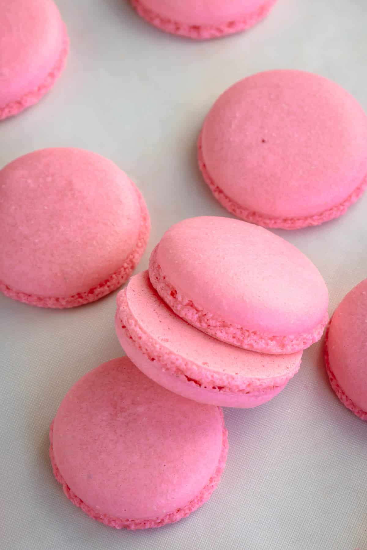 Pink macaron shells on a white surface.