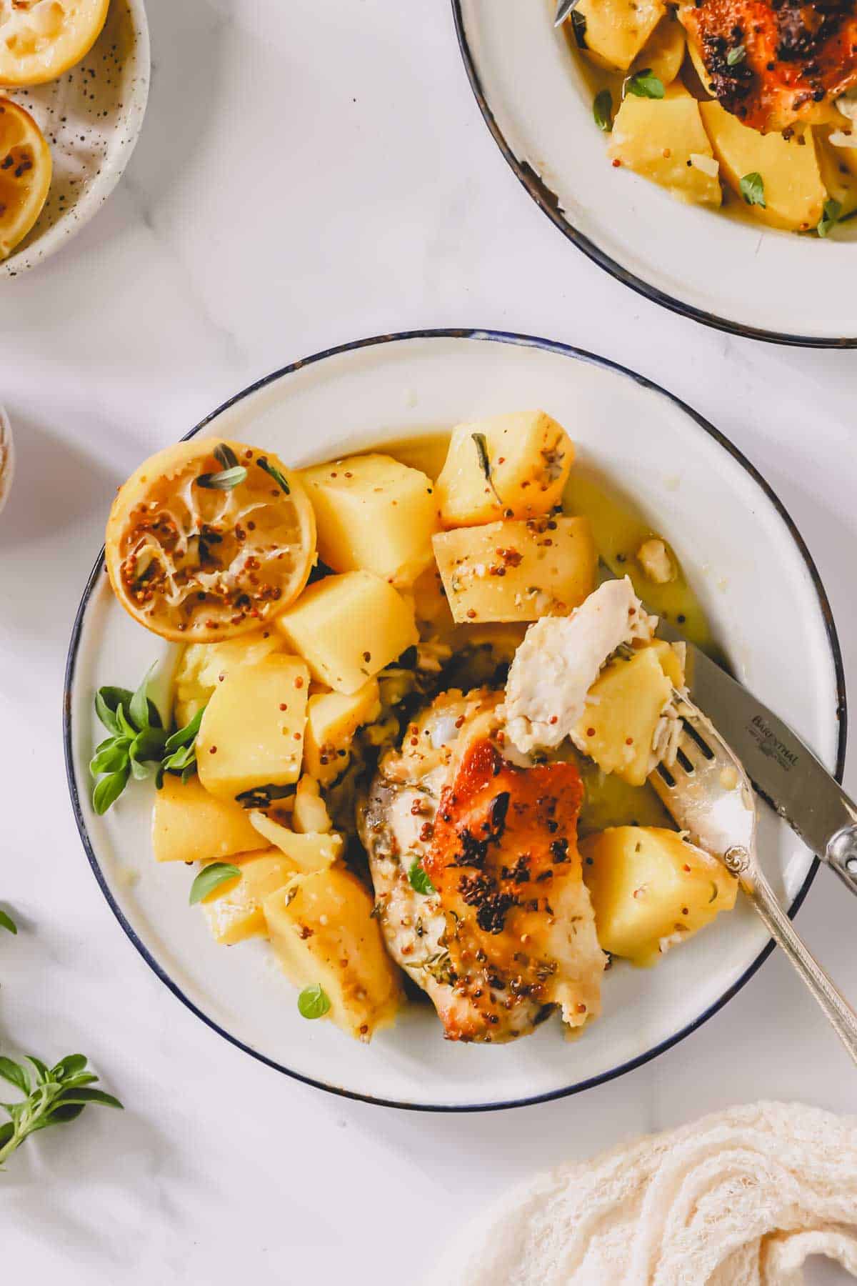A plate of Greek lemon chicken and potatoes with a fork holding a bite.
