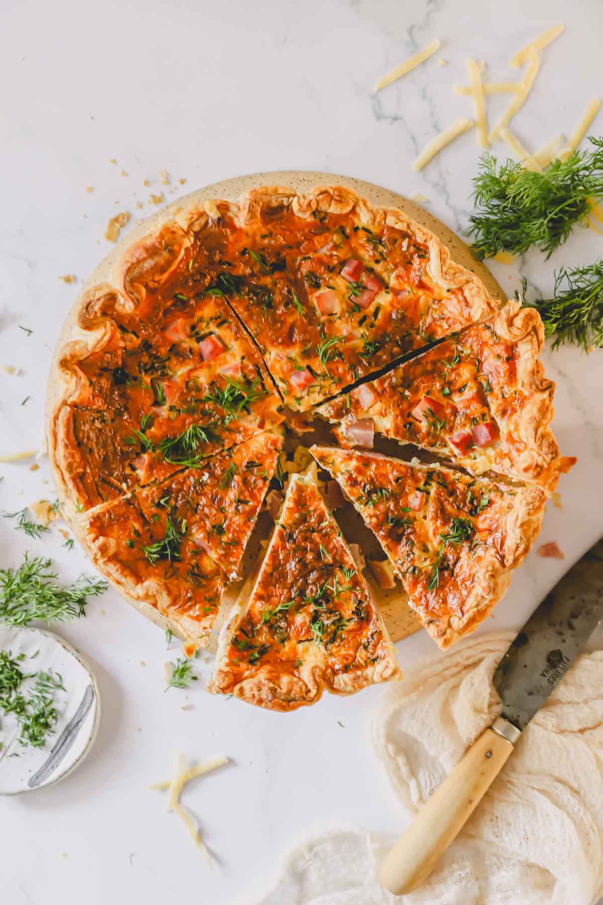 A ham and cheese quiche with four small pieces and two quarters sliced.