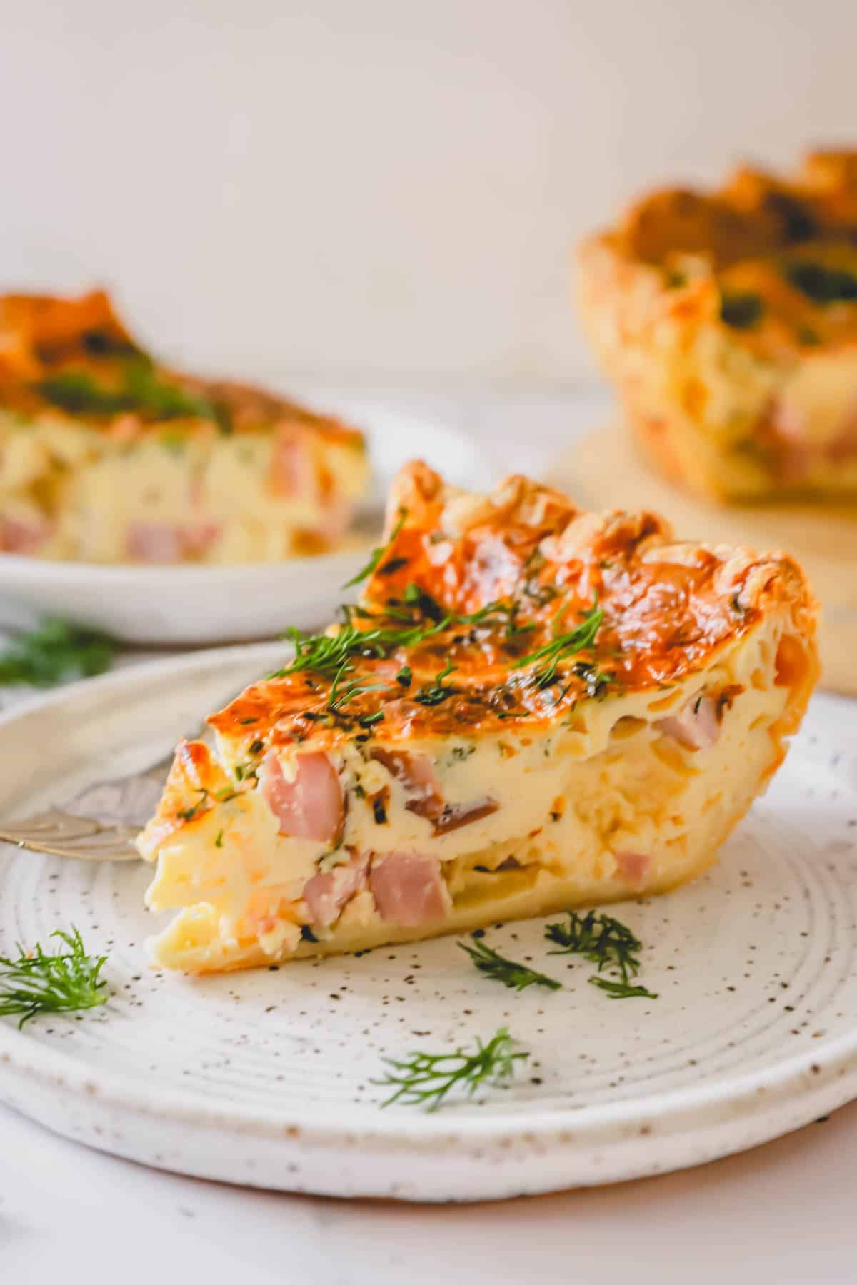 A side view of a slice of ham and cheese quiche showing the fluffy center.