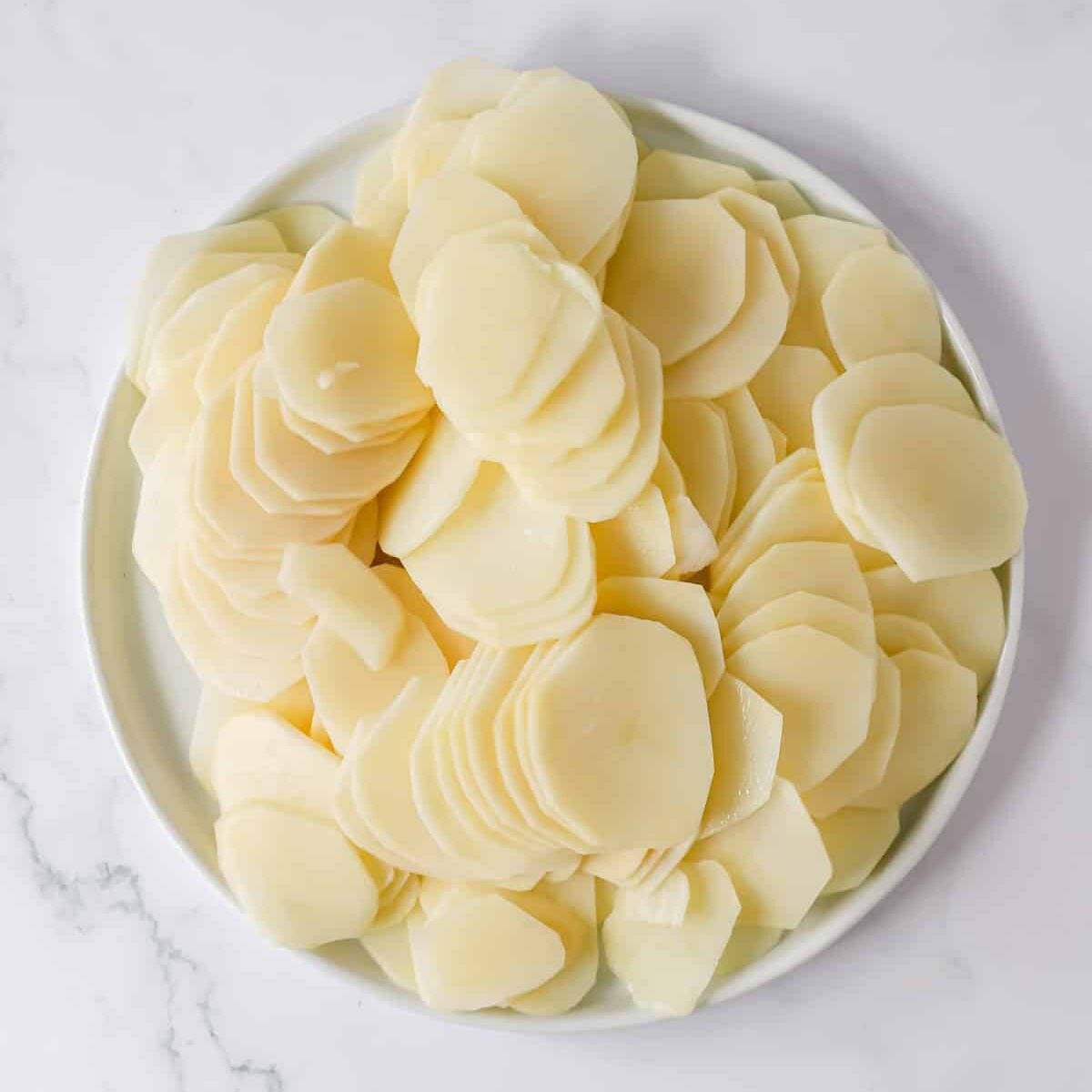 A pile of thinly sliced potatoes on a plate.