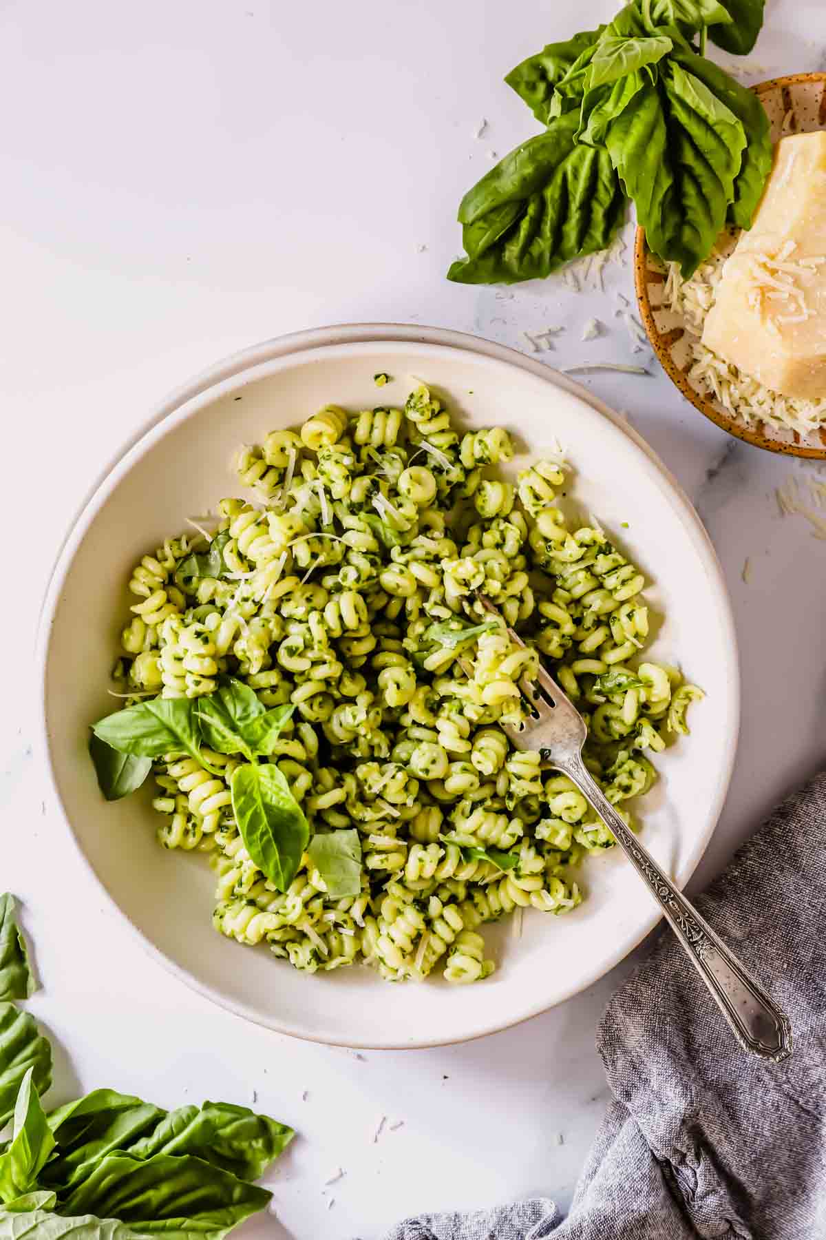 A bowl of basil pesto pasta with a fork on top.