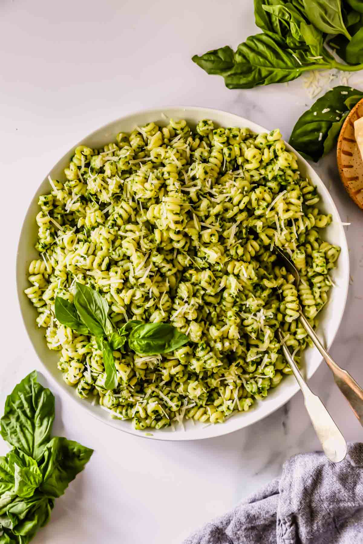 A bowl of basil pesto pasta with two forks sticking out.