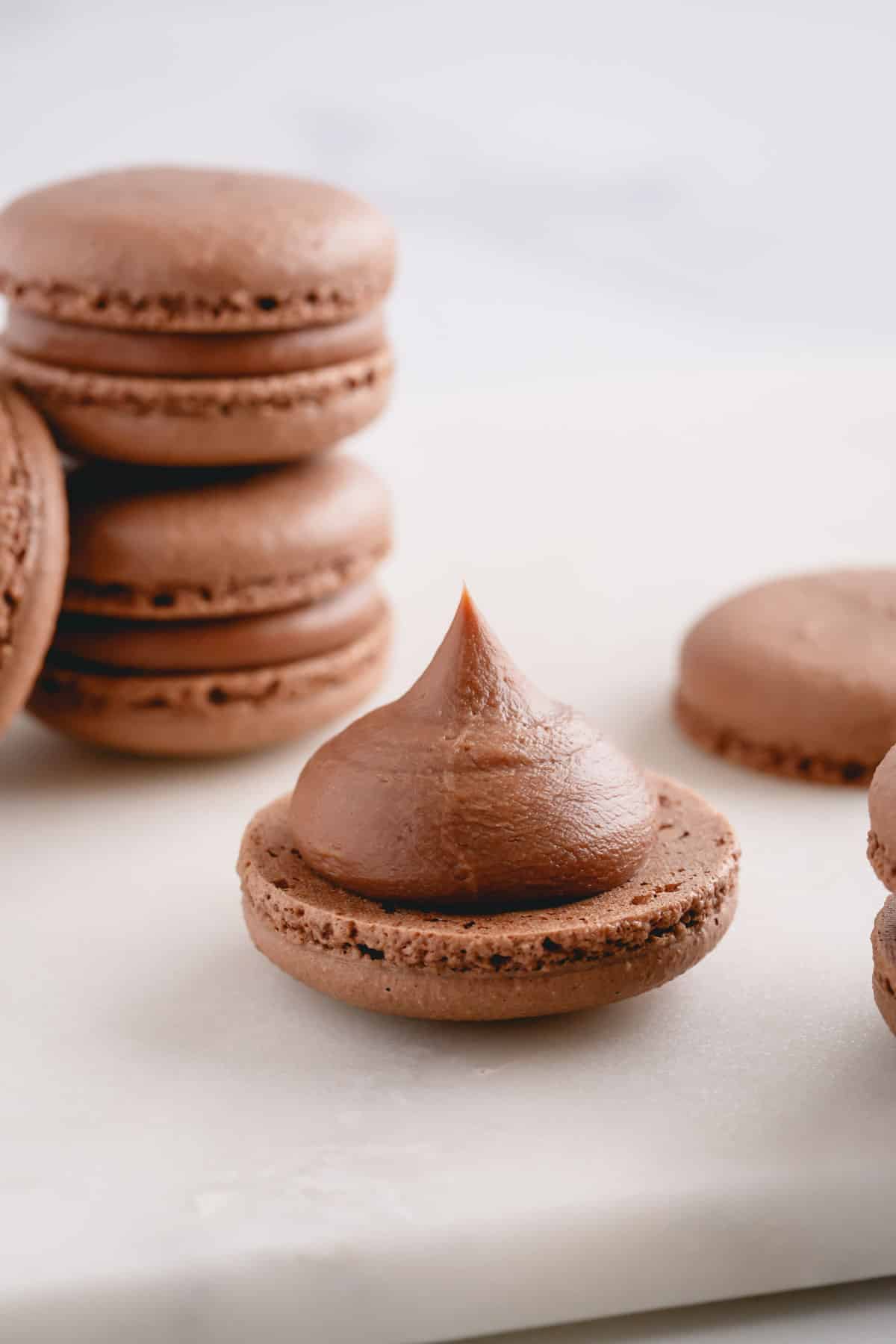 A chocolate macaron shell, bottom side up, with a dollop of chocolate filling.