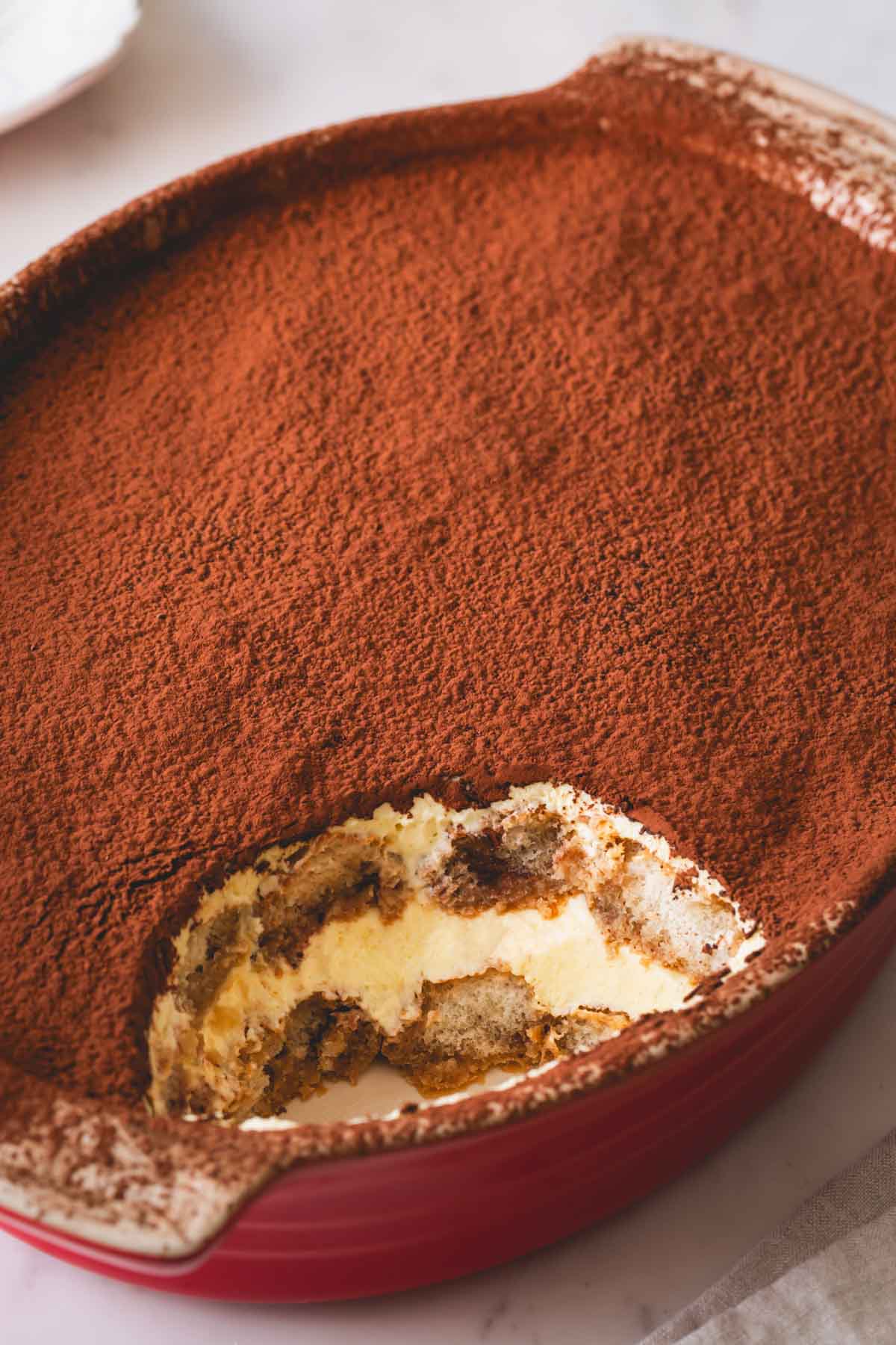 A dish of tiramisu with a serving missing.