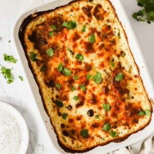 A baking dish full of cheesy scalloped potatoes topped with cilantro.