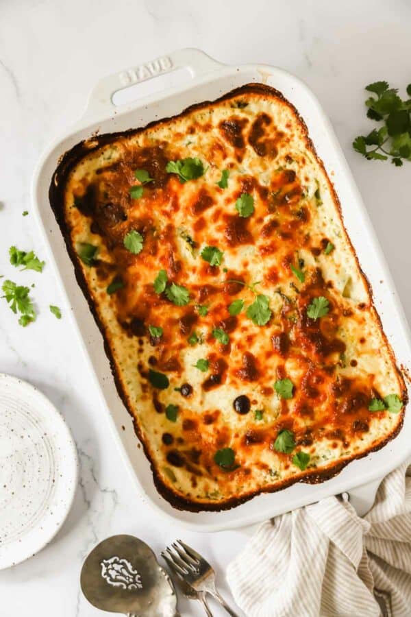A baking dish full of cheesy scalloped potatoes topped with cilantro.
