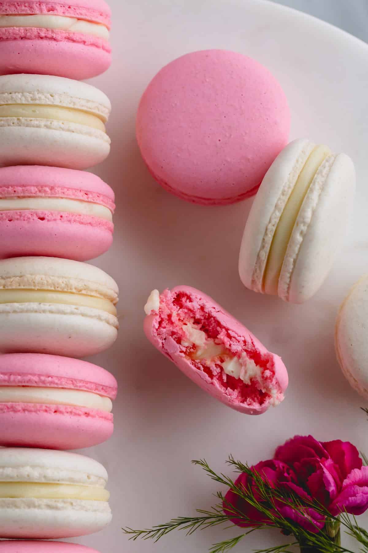White and pink macarons with one macaron has a bite out.