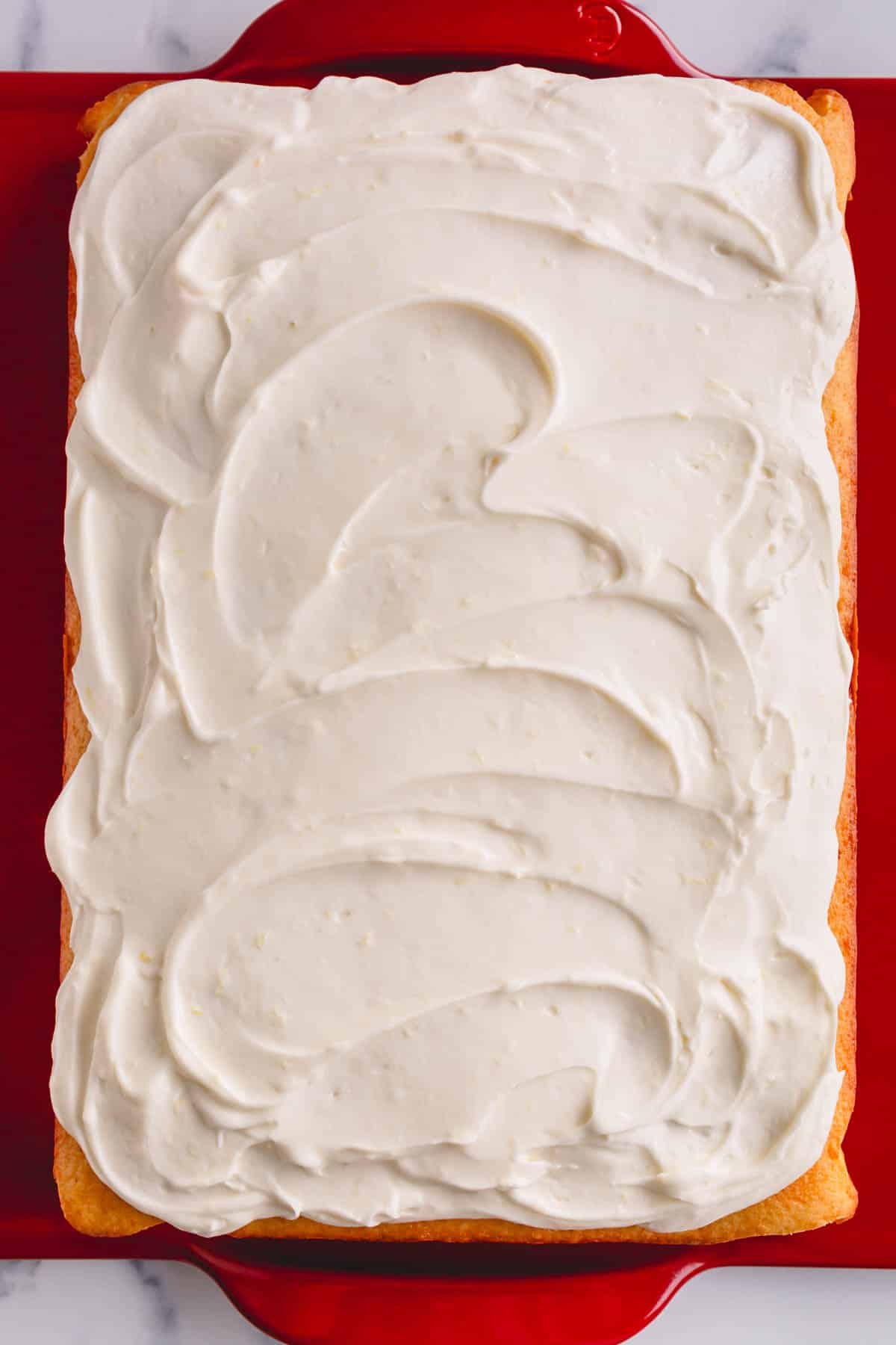 A yellow cake topped with lemon cream cheese frosting.