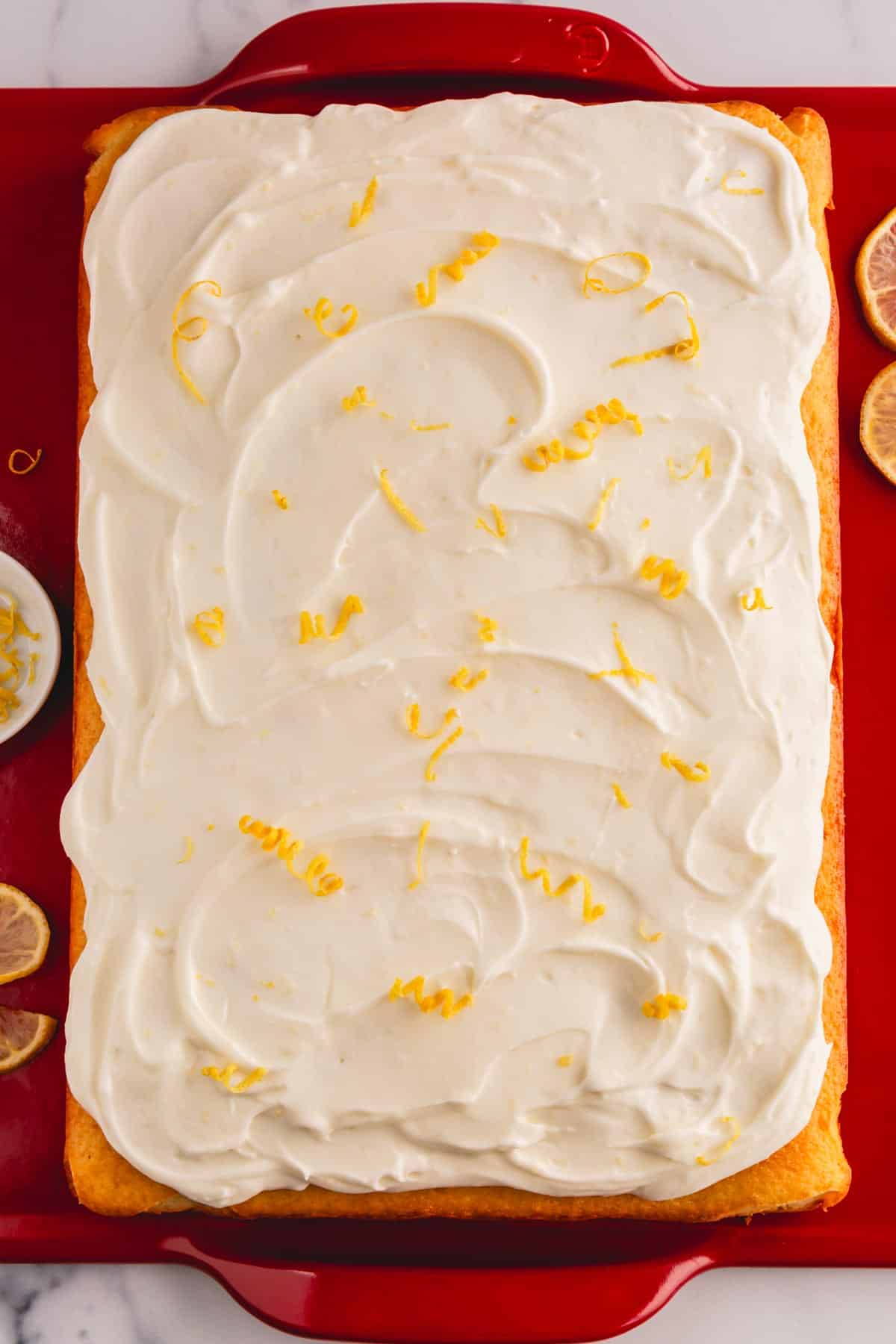 A lemon cream cheese cake topped with lemon cream cheese frosting and lemon zest.