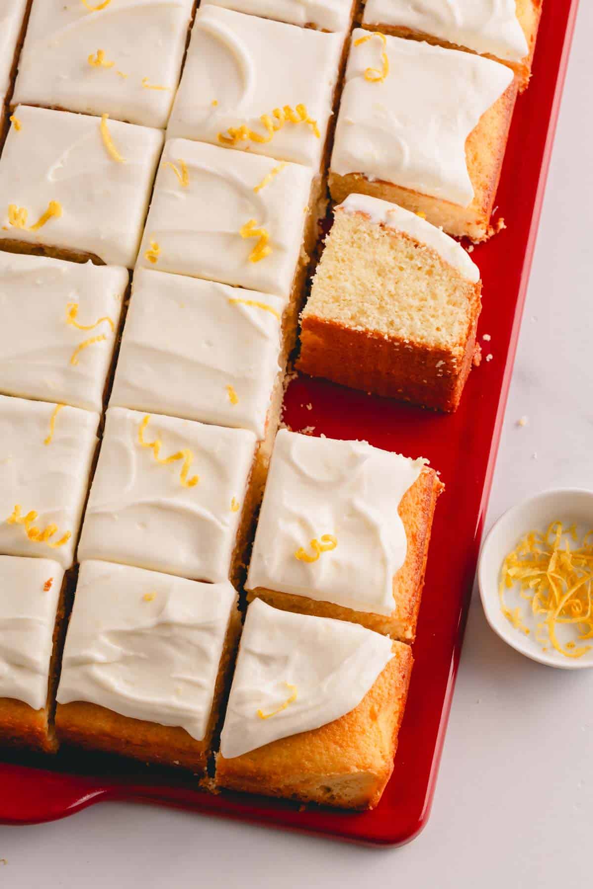Lemon sheet cake with lemon cream cheese frosting sliced into squares.
