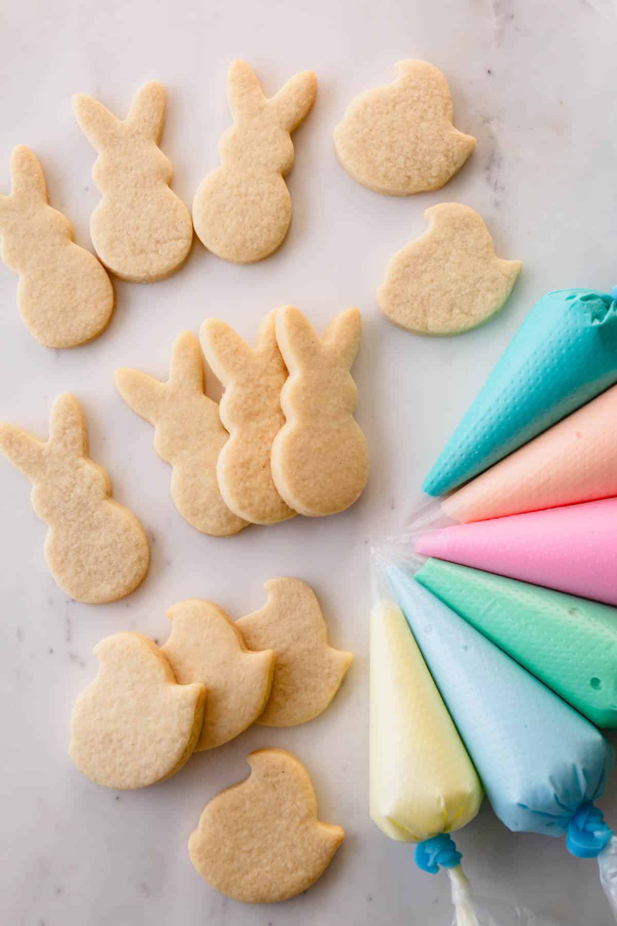 Easter sugar cookies shaped like Peeps and bunnies with pastel royal icing next to them.