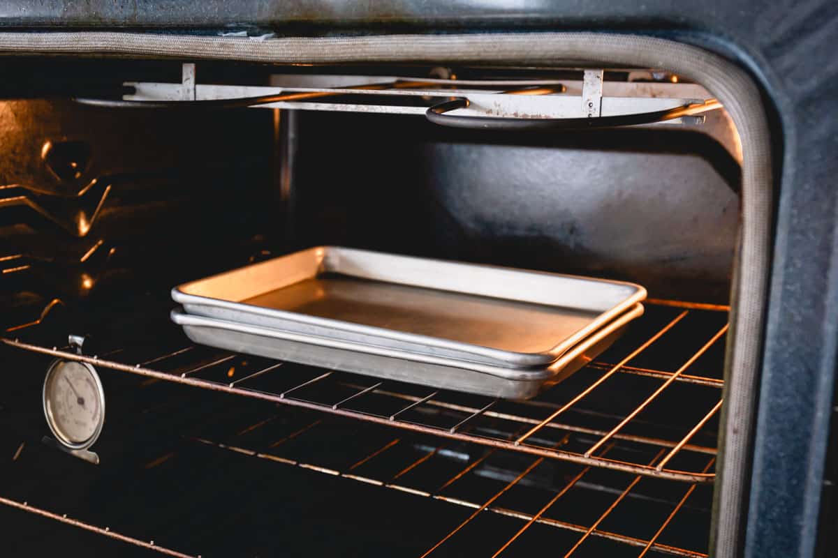 2 baking sheets with almond in between set in the oven.