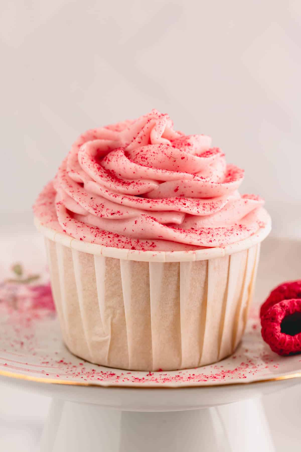 A cup of raspberry cream cheese frosting dusted with crushed raspberries.
