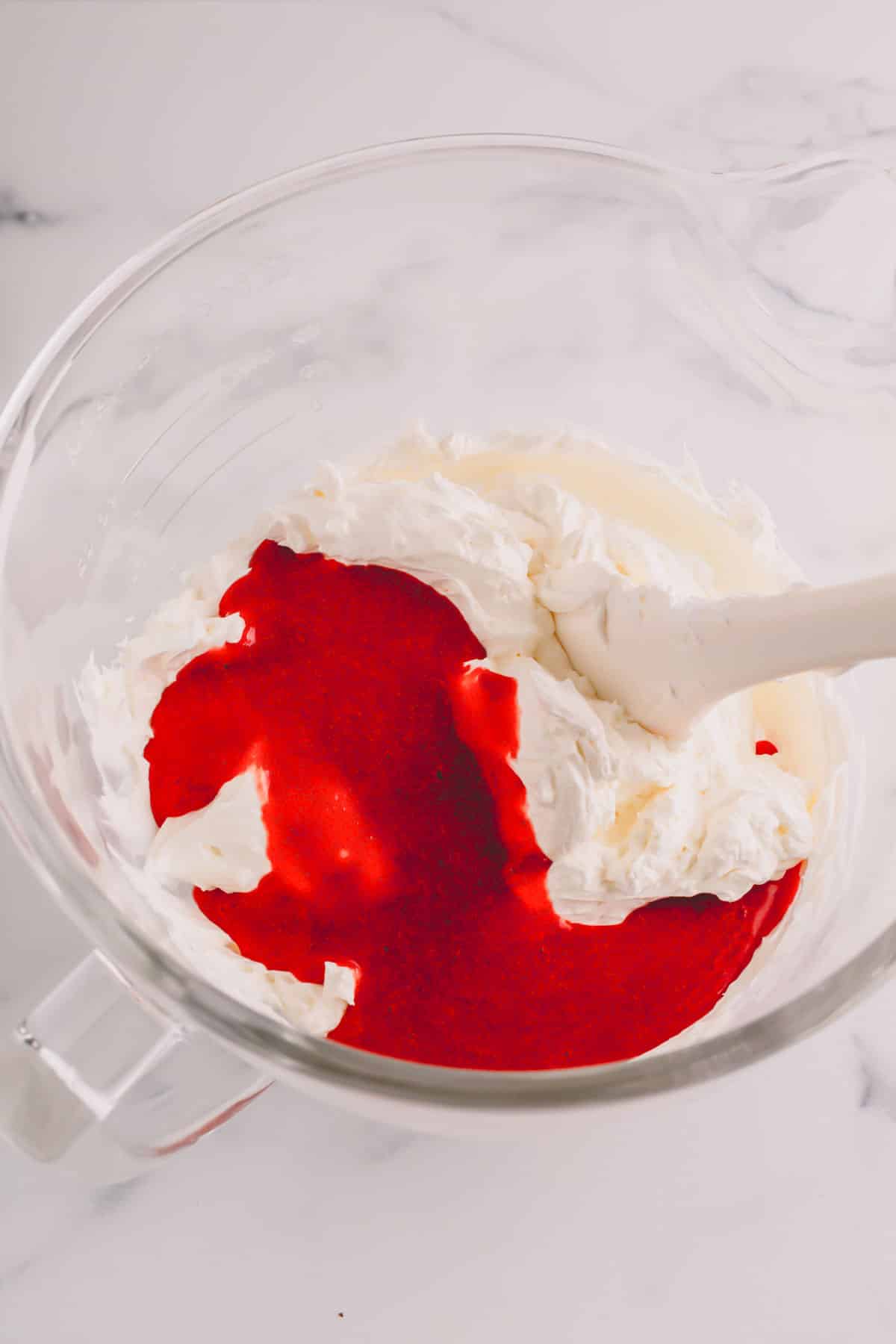 Raspberry sauce being added to buttercream.