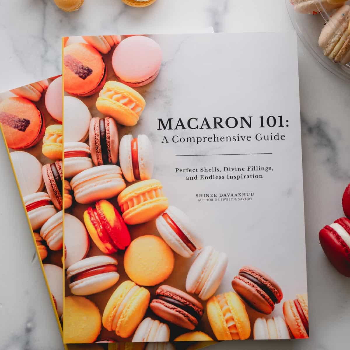 "Macaron 101" cookbook on a marble background.