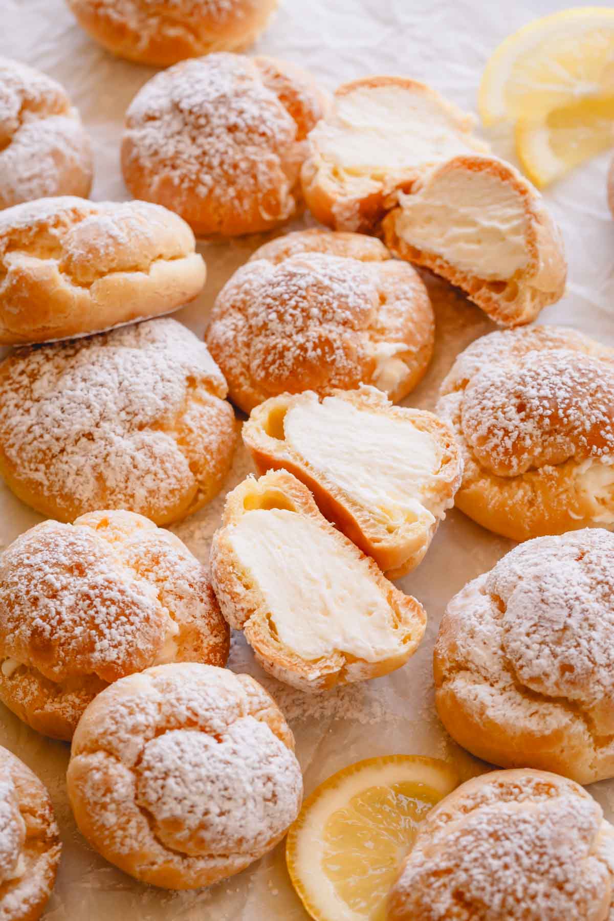 Overhead image of lemon creme puffs topped with powdered sugar with one split in half.