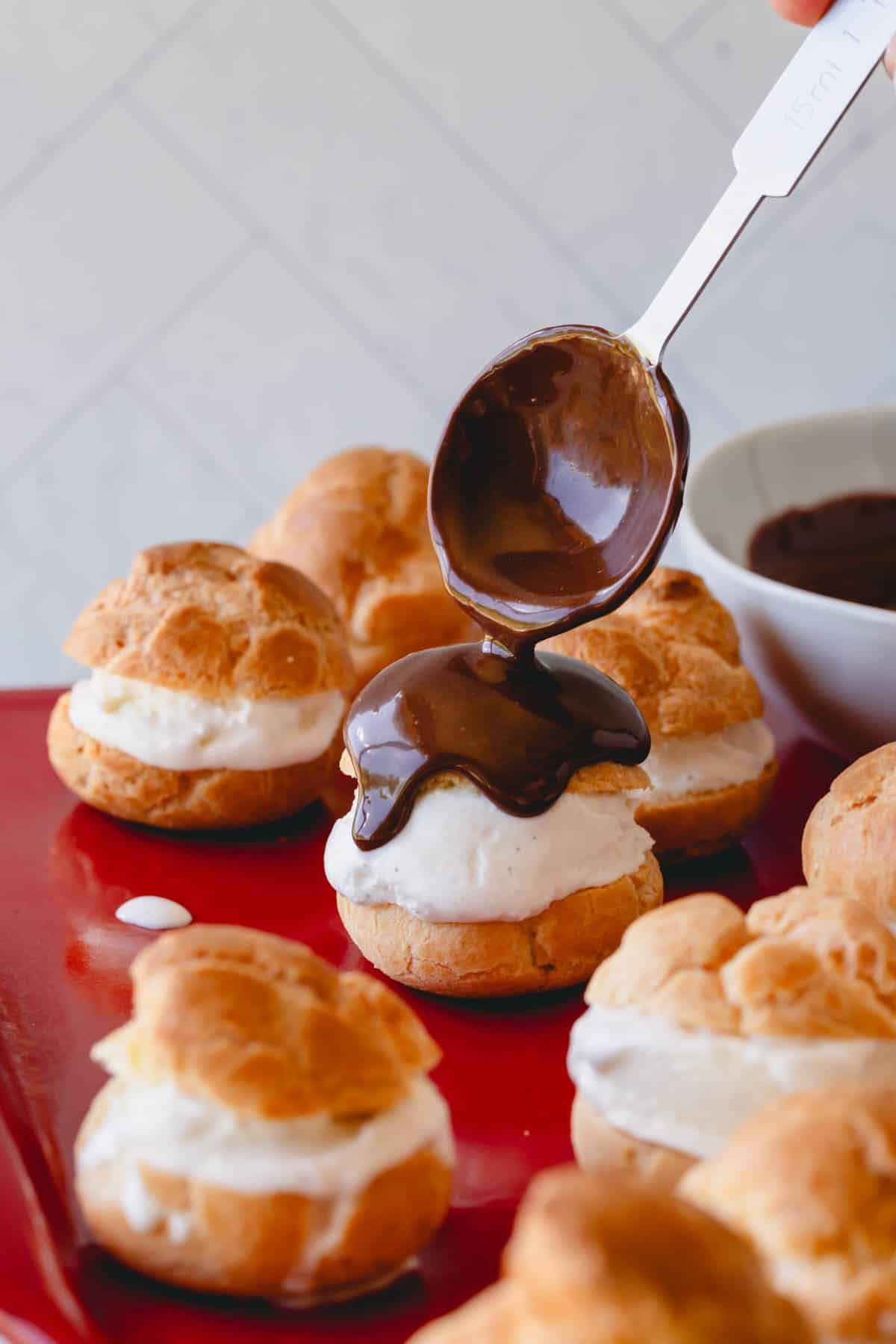 Chocolate sauce being poured over profiteroles.
