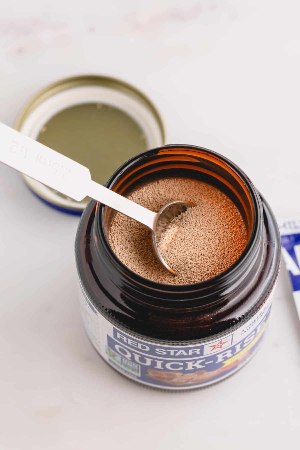 A jar of quick rise yeast with a spoon inside.