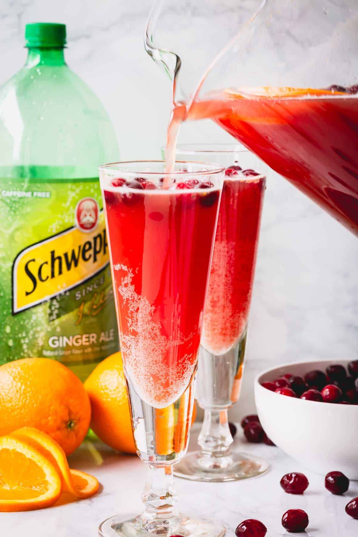 Orange cranberry spritzer being poured into two glasses.