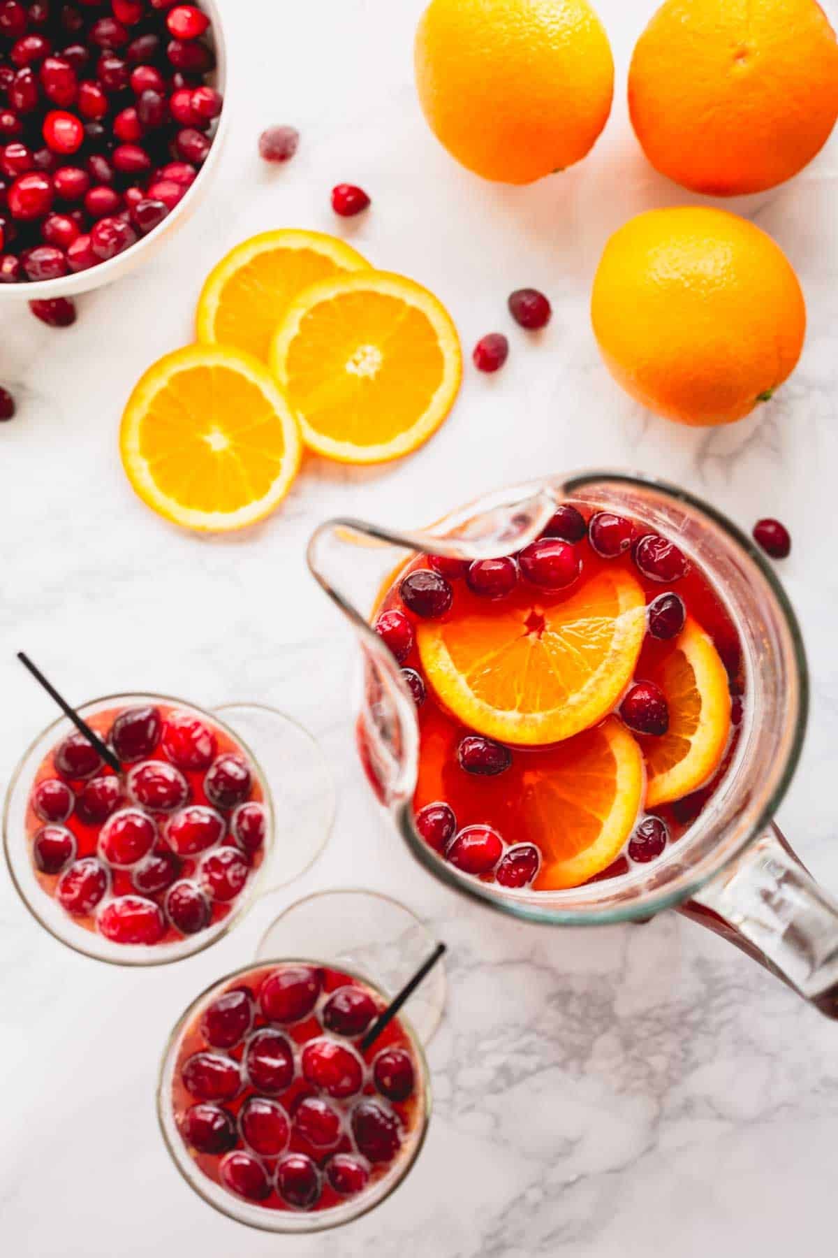 Overhead image of two glasses of orange cranberry spritzer next to a pitcher of the drink mix.