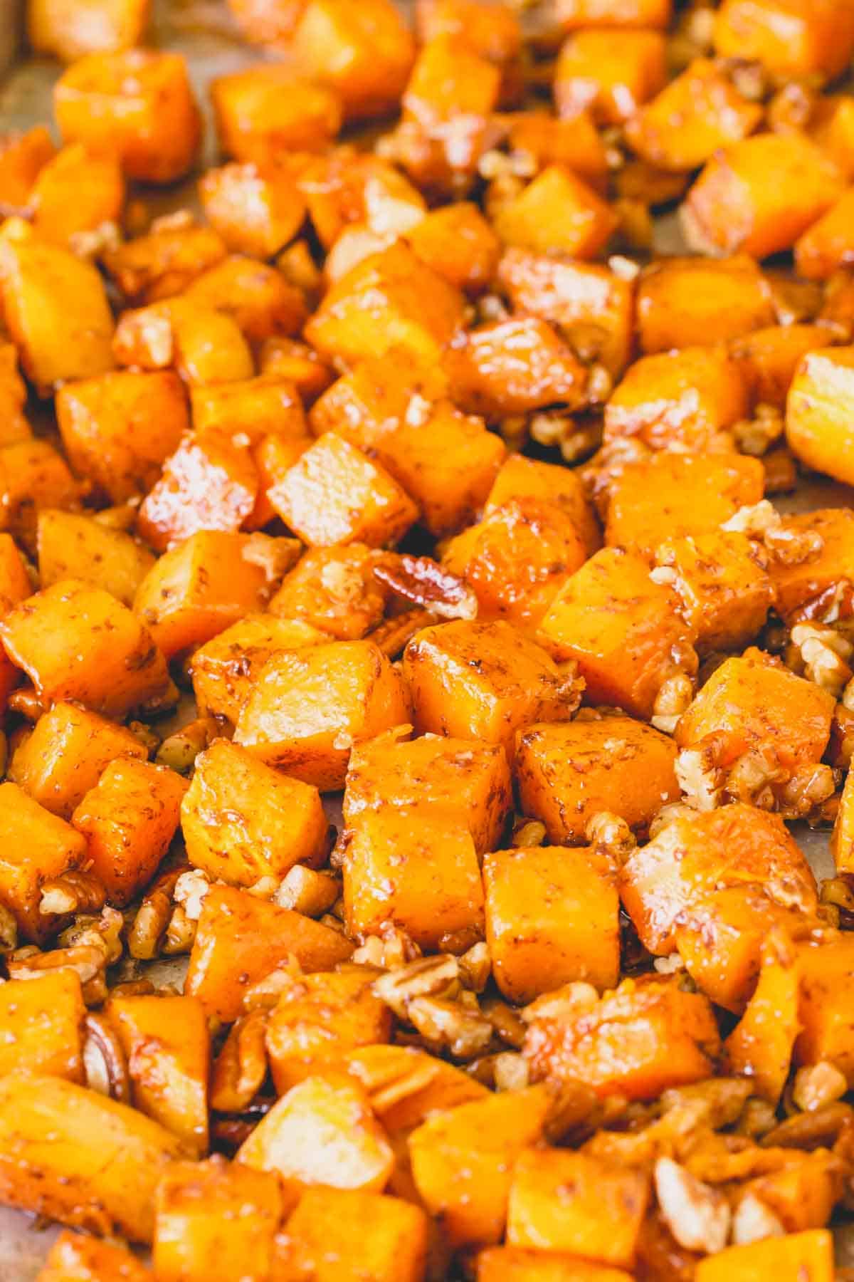 Close up image of roasted butternut squash and nuts on a baking sheet.