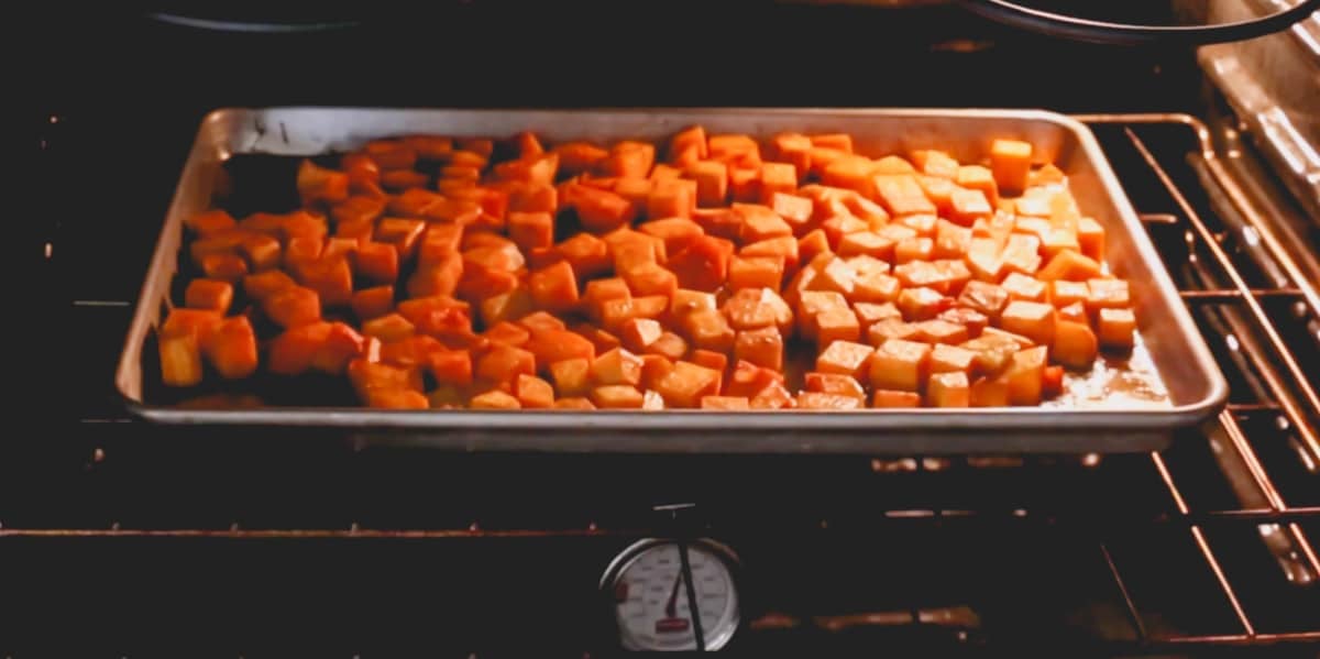 Butternut squash cubes roasting in an oven.