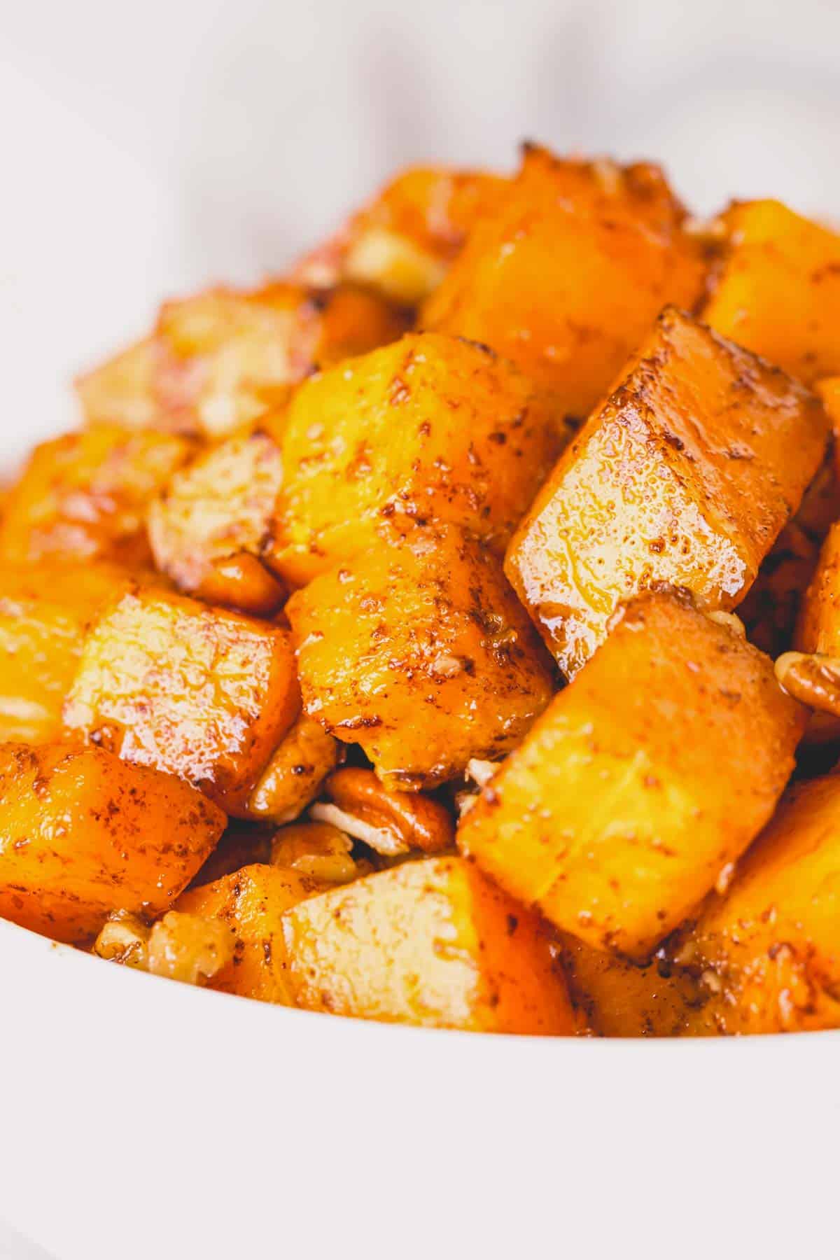Close up image of a bowl of roasted butternut squash cubes with nuts.