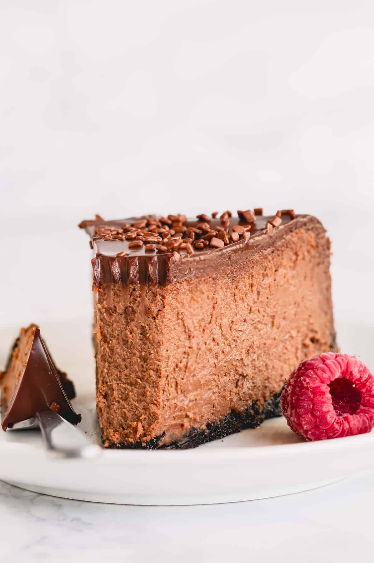 A slice of supreme chocolate cheesecake topped with chocolate ganache. 