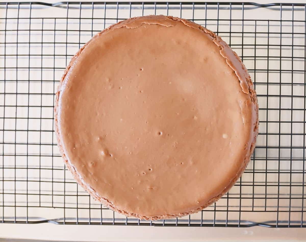 Baked chocolate cheesecake on a wire rack with springform removed.