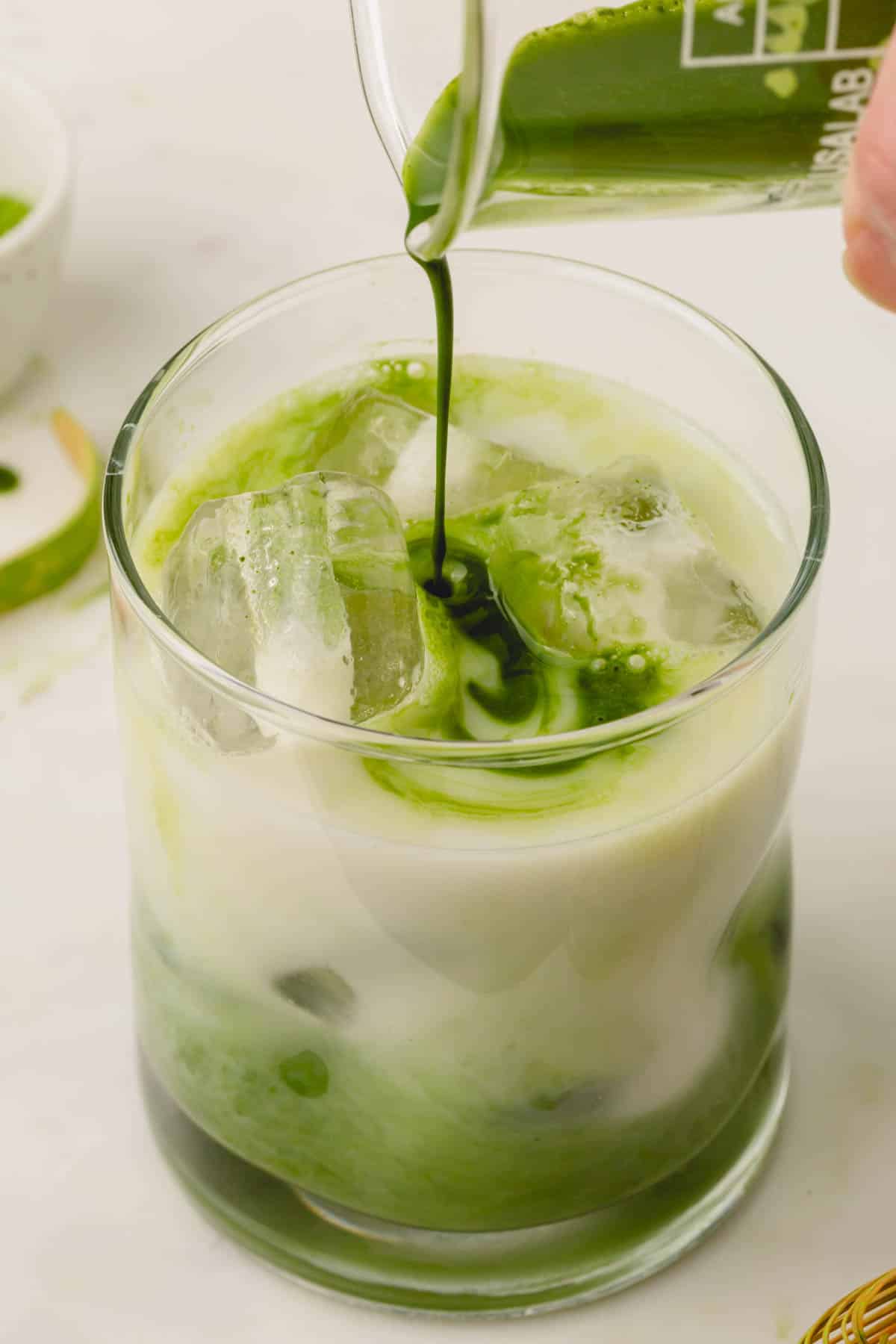 Matcha paste is poured into a glass with ice and milk.