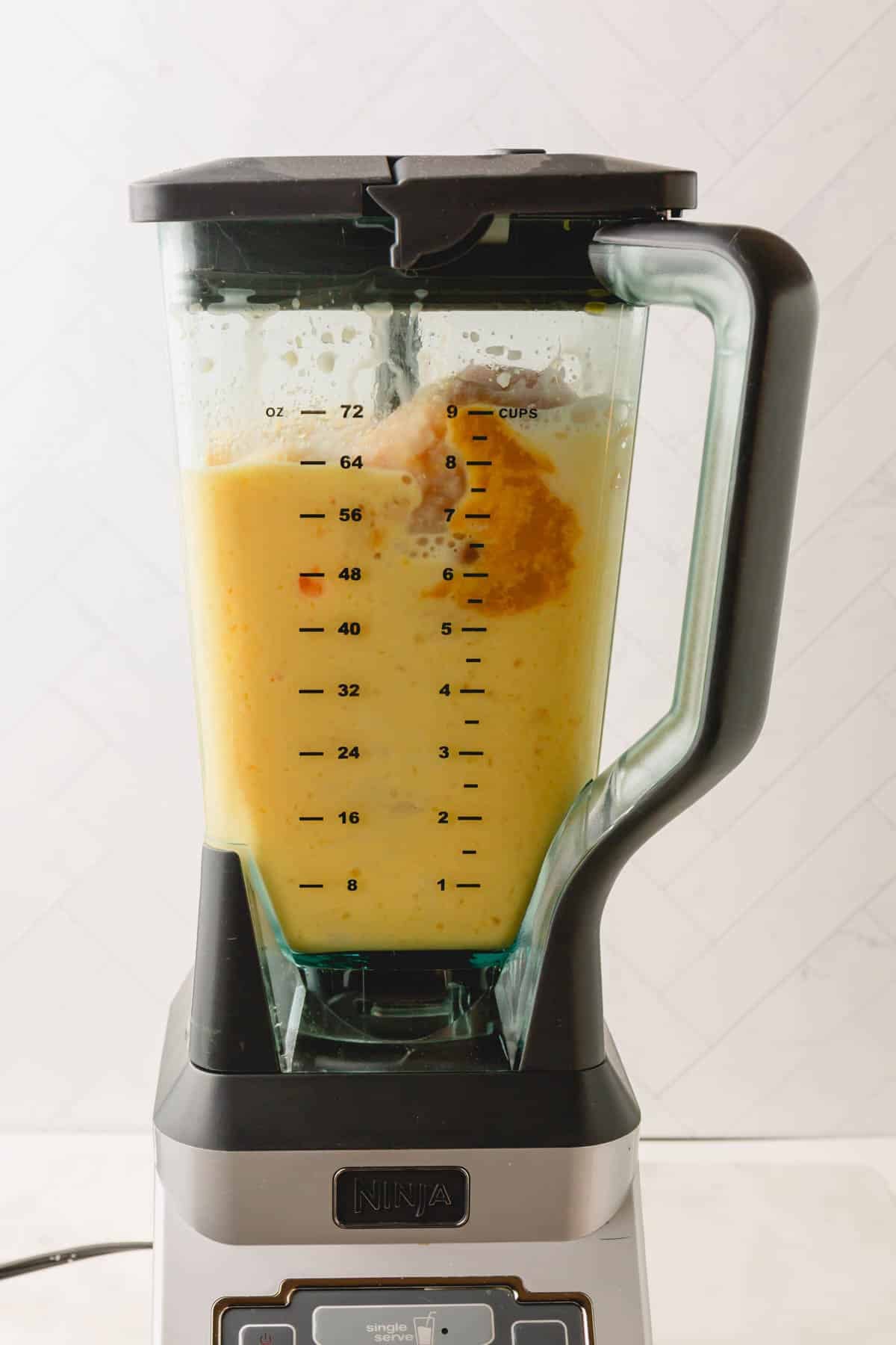 A blender with a coconut orange Julius drink mixture in it.