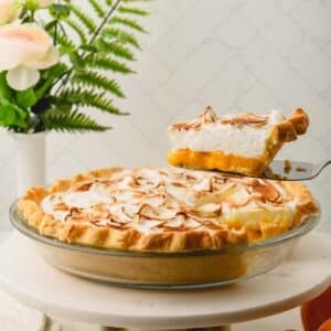 A slice of orange meringue pie being lifted from a pan full of the rest of the pie.