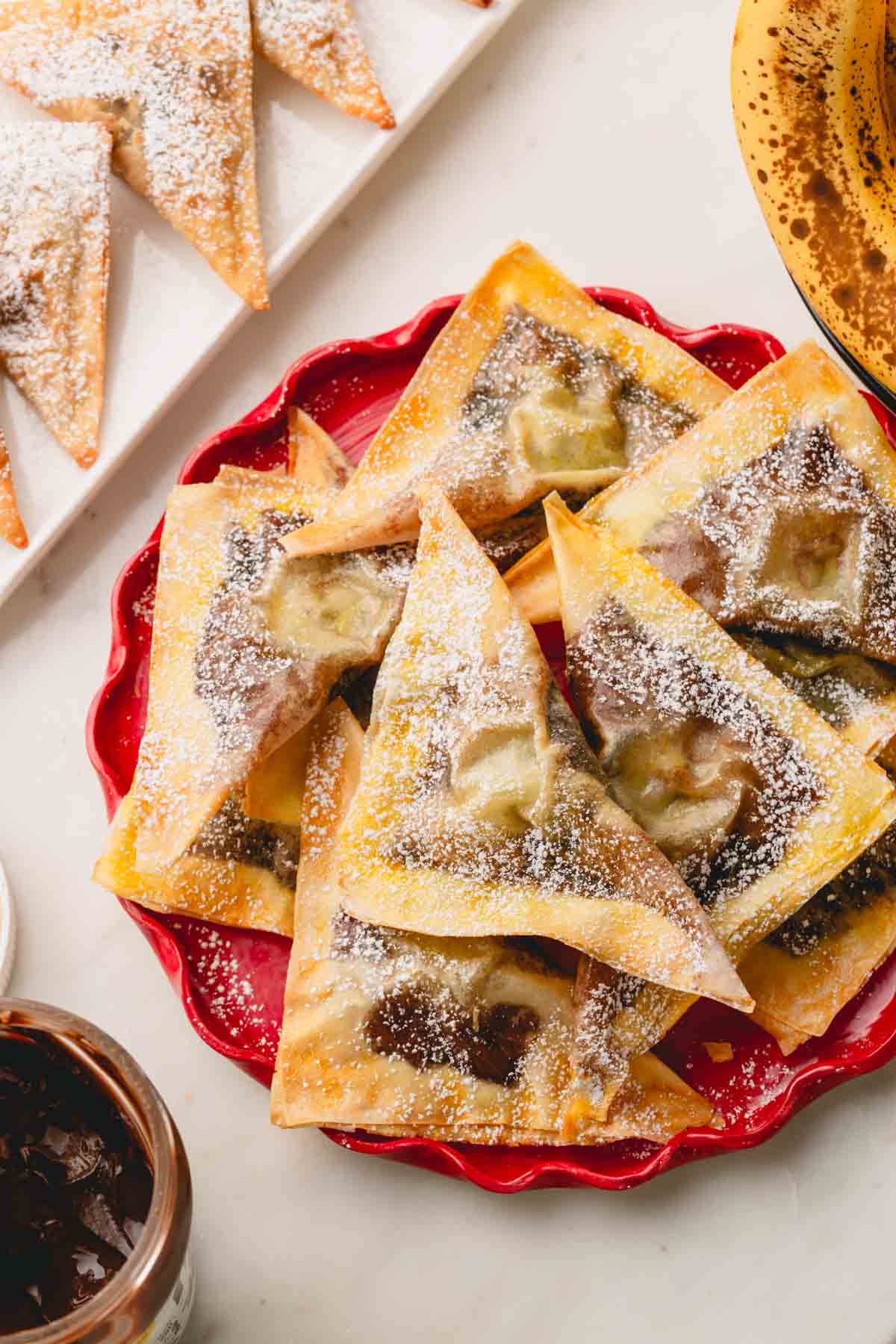 A plate of banana Nutella wontons dusted with powdered sugar.