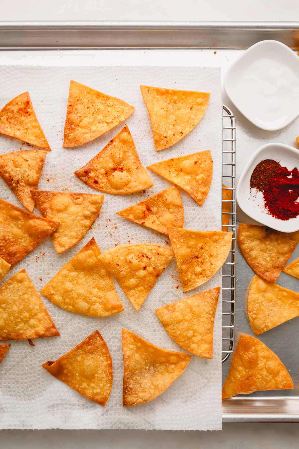 Spiced tortilla chips on a paper towel over a wire rack.
